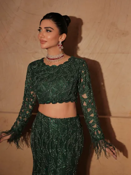 The feather details on the sleeves add a touch of drama to this elegant look. The makeup is kept clean to balance the outfit.