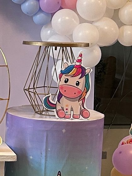 A small unicorn cutout prop placed on a themed pedestal. This detail adds to the overall magical atmosphere of a unicorn party, complemented by a geometric cake stand.
