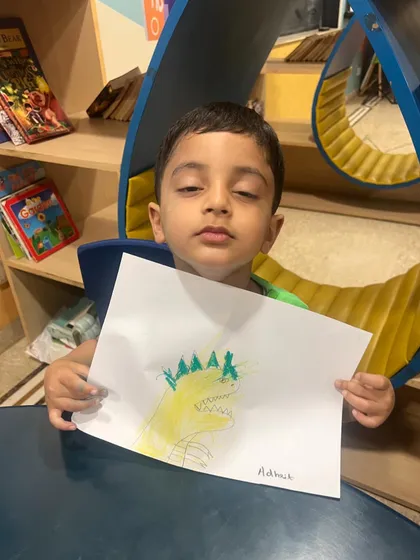 A proud student shows off his drawing of a dinosaur, created during a science camp activity. Art is a great way for children to express what they've learned.