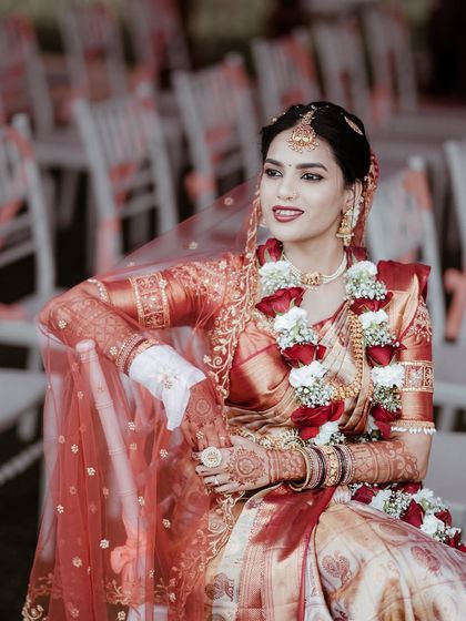 The bride, adorned in her wedding attire and jewelry, looks away with a gentle smile. This posed portrait captures her grace and the beauty of her traditional look.