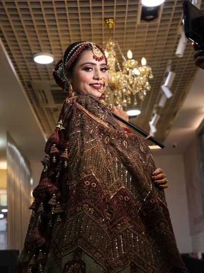 A playful and happy moment captured in the salon. The bride is ready to go, showcasing her full look with a heavily embroidered dupatta.