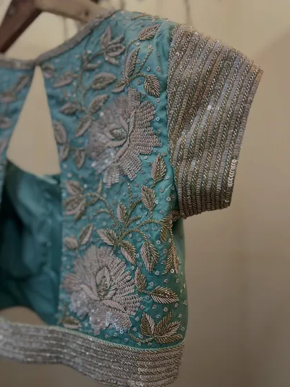A side view of the sparkly floral blouse, highlighting the heavily sequined sleeves and intricate threadwork.