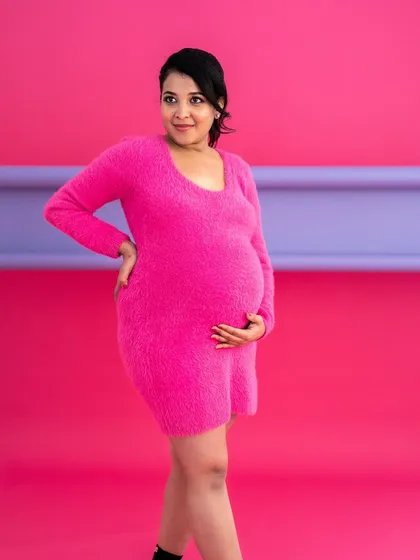 A pop of color. This vibrant pink dress against a matching backdrop creates a bold, modern, and fashion-forward maternity portrait.