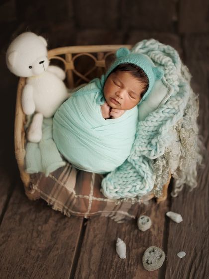 A minty dream. This setup combines a rustic wooden basket and floor with soft, mint-colored knits and a cute bear bonnet for a cozy, woodland feel.