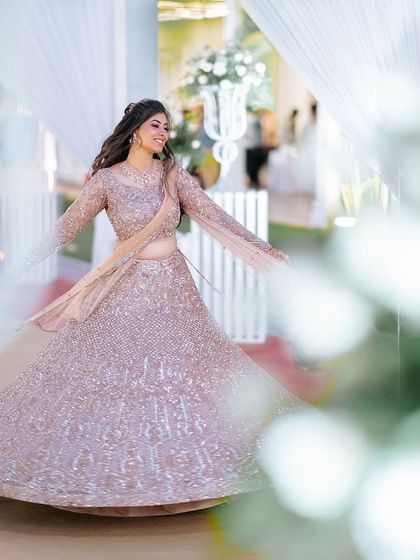 A beautiful twirling shot of a bride in a shimmering blush pink lehenga, perfect for a reception. The makeup is soft and romantic to match.