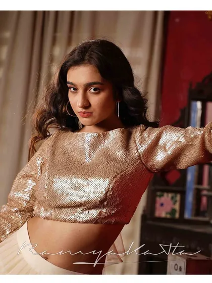 A confident portrait showcasing the all-over sequin work on the beige crop top. The modern cut and shimmering texture make it a party-ready piece.