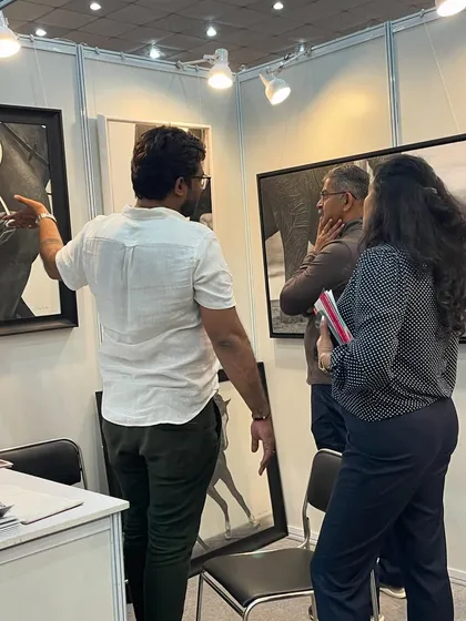 Explaining the nuances of my artwork to interested visitors during an exhibition. These interactions are incredibly valuable.