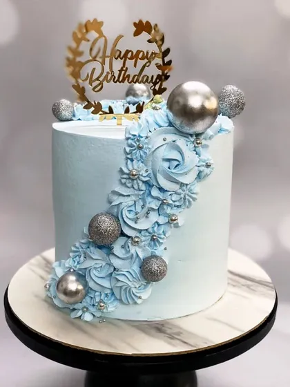 A soft blue whipped cream cake decorated with smooth swirls, delicate pearls, and sparkling silver balls. It's a touch of wintery elegance for a special birthday.