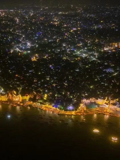 This wide aerial shot captures the entire stretch of Varanasi's ghats illuminated during Dev Deepawali. It shows how the whole city comes alive with light, lining the sacred river.