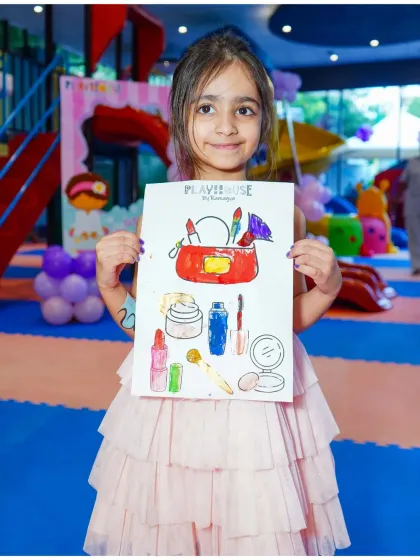 A proud young artist shows off her coloring of a makeup kit, a perfect activity for our pamper-themed parties.