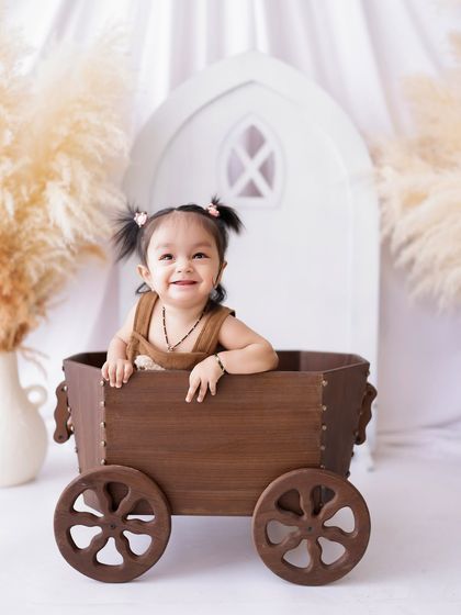 Pigtails and a happy smile! This little girl's cheerful personality shines as she plays in a rustic wooden cart prop.