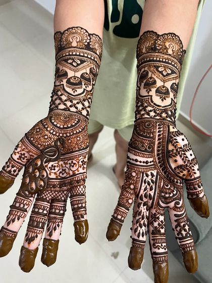 A beautiful design featuring jhumka (earring) motifs and a delicate bow on the palm.