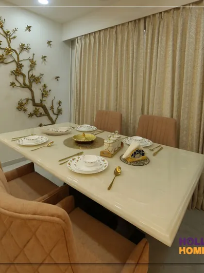The dining area in our modern Maharashtrian project, featuring a beautiful metal wall art piece depicting a tree with birds. This element adds a touch of nature and artistry to the elegant space.