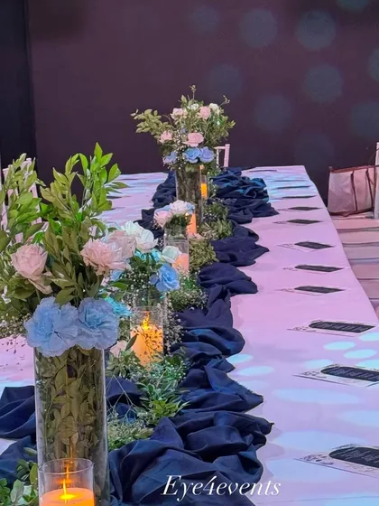 Another angle of the long table decorated in a blue and white theme. The white Tiffany chairs complement the white tablecloth, making the blue floral arrangements and runner stand out beautifully.