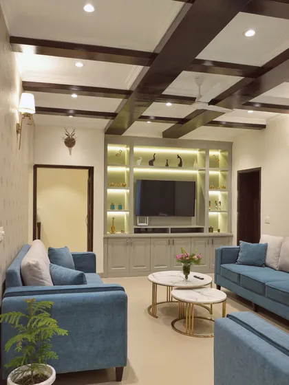 For this homestay in Dehradun, we designed a cozy yet refined living area. The coffered ceiling features a structural beam cladded in exquisite veneer, which we balanced with a second, identical beam. The design combines a muted color palette with vibrant teal sofas for a welcoming feel.