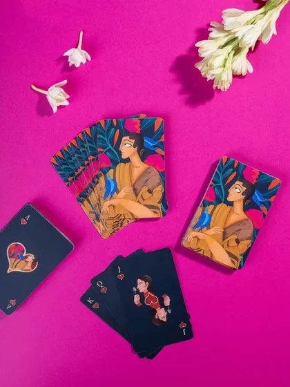 A vibrant flat lay of illustrated playing cards on a pink background. The playful arrangement and bright colors create a fun and engaging image.