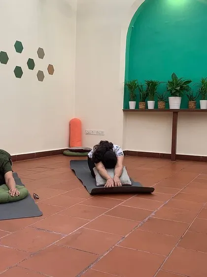 Participants using bolsters and pillows to find comfort and depth in a forward fold. My classes emphasize using props to support the body, allowing for a deeper release and relaxation.