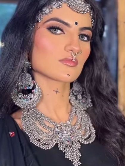 A model showcasing a dramatic look with a heavy, layered oxidised silver necklace, matching oversized earrings, and a mathapatti.