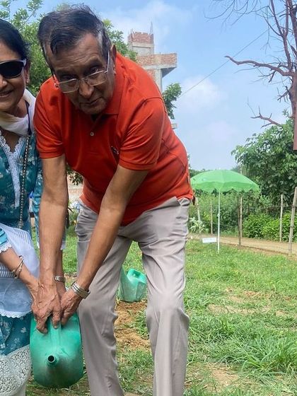 An elderly couple from the DLF Senior Citizen Council waters a sapling together, a beautiful moment from our decade-long collaboration with their group.