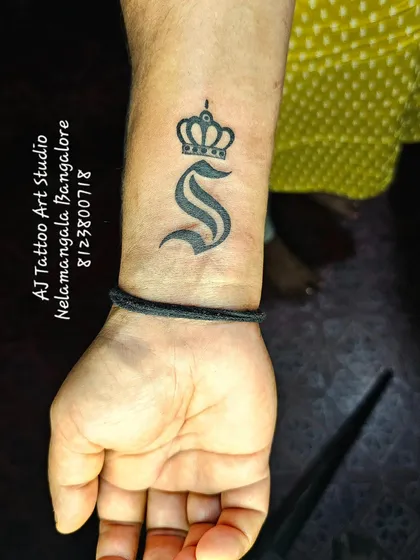 A bold initial 'S' with a crown on the wrist, a simple and royal design.