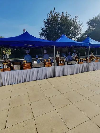 A wide view of the outdoor catering arrangement for Indigo Airlines. Multiple canopies and long buffet tables are set up to handle a large number of guests efficiently, demonstrating our capacity for large-scale corporate catering logistics.