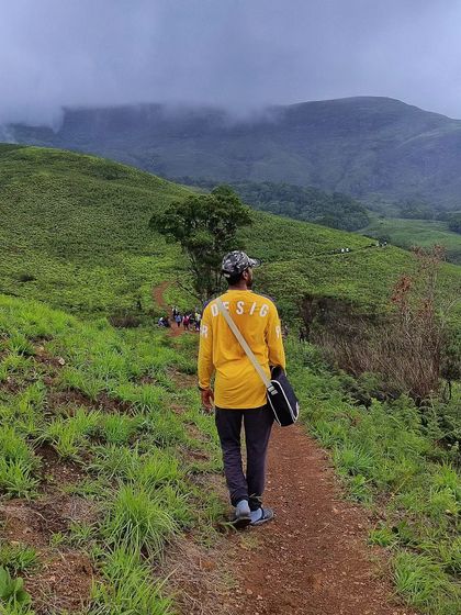 A lone trekker on the path to Kudremukha, with the famous "Ontimara" (lone tree) in the distance. A journey of solitude and strength.