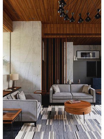 The lounge's interior design features a mix of natural materials, including wood, stone, and a patterned rug that complements the neutral-toned furniture.
