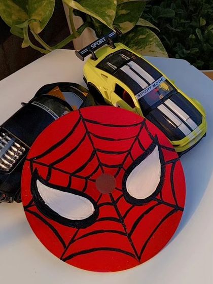 An upcycled CD painted with the iconic Spider-Man mask. This is a fun piece of pop-culture art perfect for decorating a fan's room.