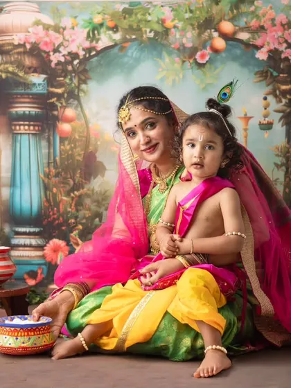 A beautiful portrait celebrating Janmashtami with Yashoda and her little Krishna. The setup includes traditional elements like pots of butter to make the scene complete.