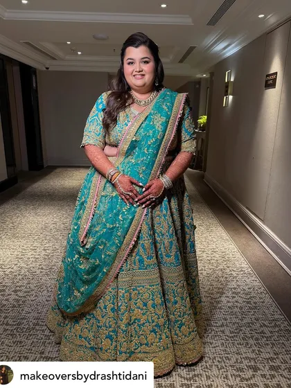 A full-length view showing the entire ensemble. The makeup is perfectly balanced to complement the rich colors and heavy embroidery of her outfit.