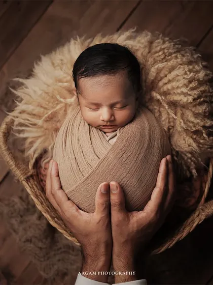 A tender close-up of a newborn, swaddled and held securely in their father's hands. This image highlights the delicate details and profound sense of safety in those first few days.