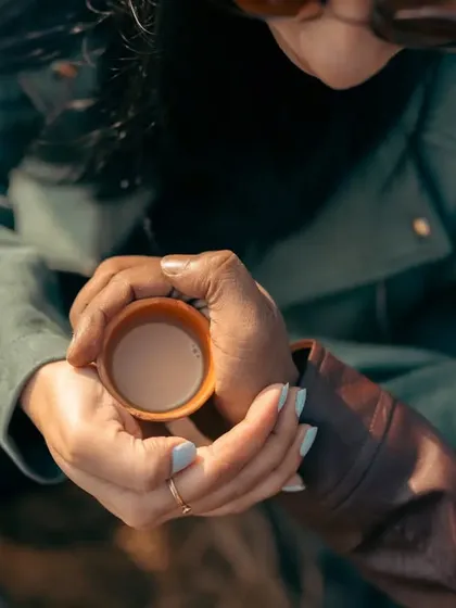 Love is sharing a warm cup of chai on a cool morning. This close-up focuses on their hands intertwined around a traditional clay cup, a simple and beautiful symbol of their bond.
