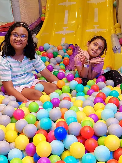 Friends enjoying a relaxing moment in the ball pit after an exciting time on the slides.