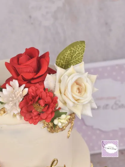 A close-up of the handmade red and white sugar flowers on the engagement cake.
