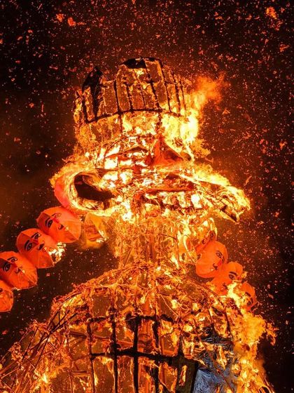 A dramatic close-up of the Ravana effigy as it is engulfed in flames, sparks flying into the night sky.