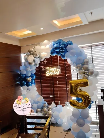 A blue, white, and silver balloon ring with a neon sign for a 5th birthday party.