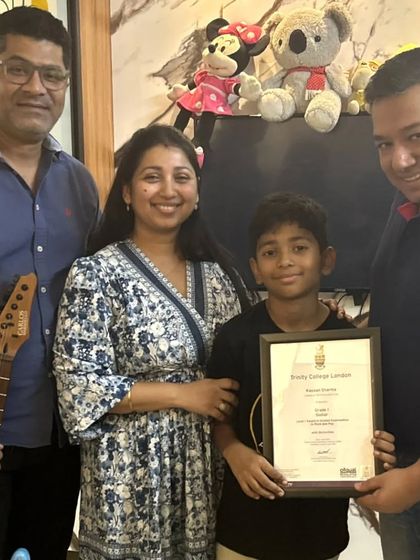 **Ready to Rock.** This young guitarist and his family celebrate his achievement. We provide the path for students to become confident performers on their chosen instrument.