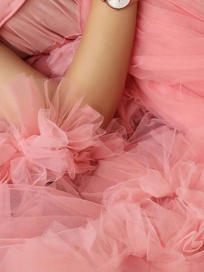 A macro shot capturing the delicate floral details and soft ruffles of a pink maternity gown, highlighting the quality and beauty of the outfits in my client closet.