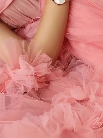 A macro shot capturing the delicate floral details and soft ruffles of a pink maternity gown, highlighting the quality and beauty of the outfits in my client closet.