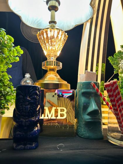 A collection of our unique tiki mugs and decor, including a vintage-style lamp, adding character to the bar.