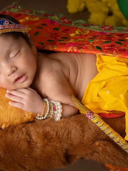 Peacefully dreaming. This pose showcases the baby's serene expression and the beautiful, traditional costume.
