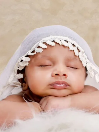 A close-up version of the lace veil portrait, focusing on the baby's peaceful expression and pouty lips.