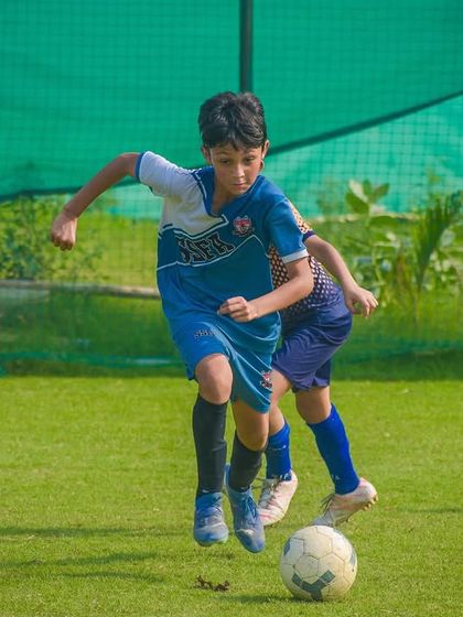 An athlete dribbles the ball with speed and control, navigating the pitch during an intense moment of a Pride Cup match.