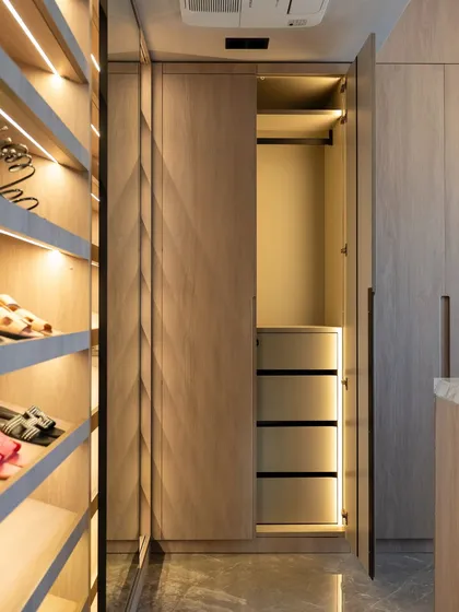 This walk-in closet features a mix of open and closed storage, with integrated lighting to highlight the contents. The warm wood finish and thoughtful layout create a luxurious and highly functional dressing area.
