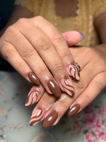 A chic and trendy design featuring abstract swirls in a coffee-brown shade over a nude base. It's a modern and sophisticated take on neutral nail art.