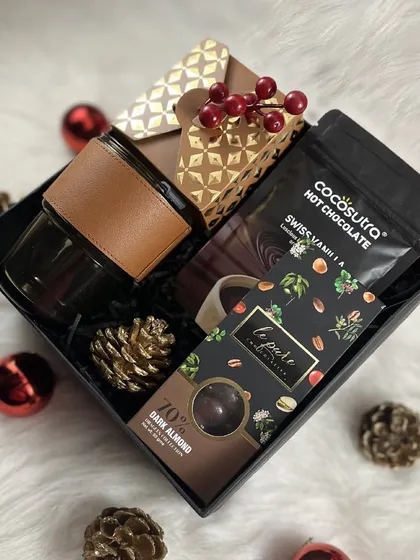 A closer, top-down view of the 'Cozy at Home' hamper, highlighting the rich textures and warm tones of the products inside.