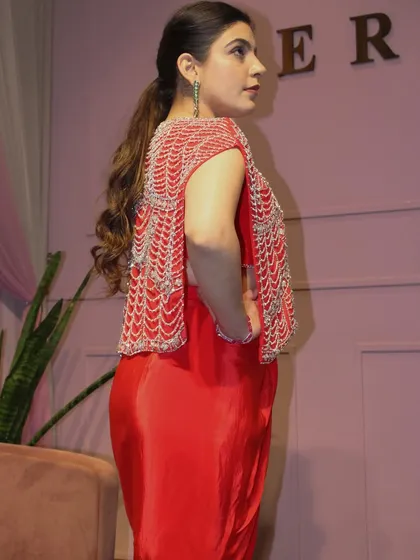 A side view of the red draped skirt set, showing the detail on the back of the jacket.