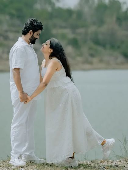 A playful and sweet moment during a pre-wedding shoot by the lake. The bride's pose adds a touch of fun and personality to this romantic portrait.