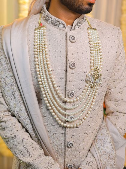 A close-up detail shot of the groom's multi-layered pearl necklace, an important accessory.
