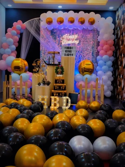 A closer view of the pastel and gold birthday decorations. You can see the "HBD" light-up letters, which add a personal and bright touch to the party decor.